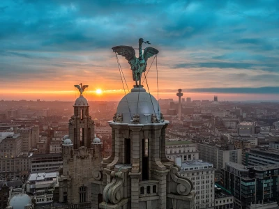 Madrid cityscape at sunset featuring the Metropolis Building with a winged statue atop its dome, bathed in orange light fading to blue.